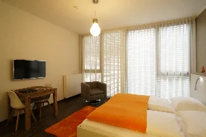 Studio Large – Doppelbett, Arbeitsplatz und Sessel mit Blick ins Bad | Boardinghouse Offenbach